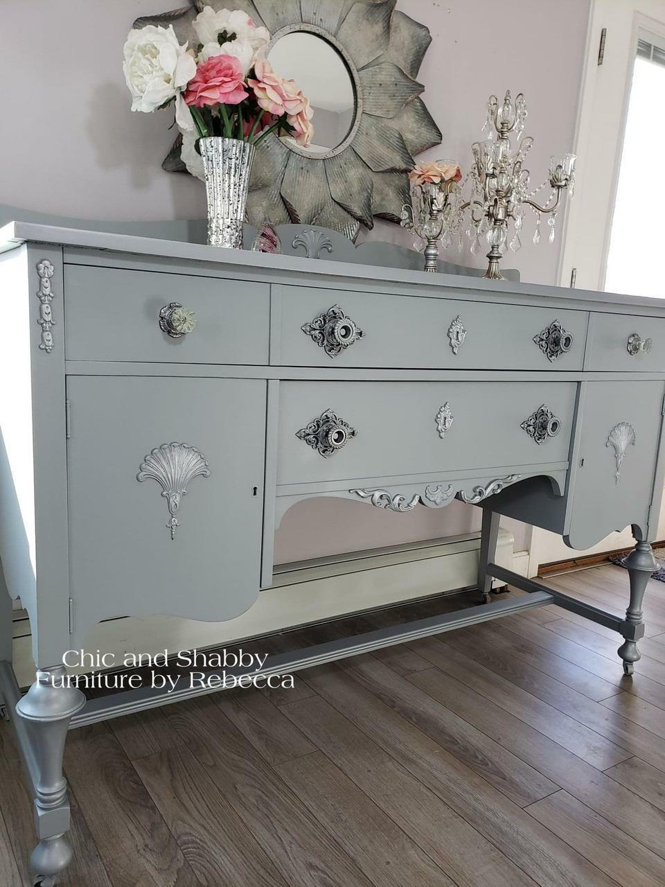 Dixie Belle Paint Manatee Gray Chalk Mineral Paint is the perfect paint for any DIY project! Light Gray Chalk Painted desk with Silver Accents. Staged with a candle stick holder and vase with flowers.