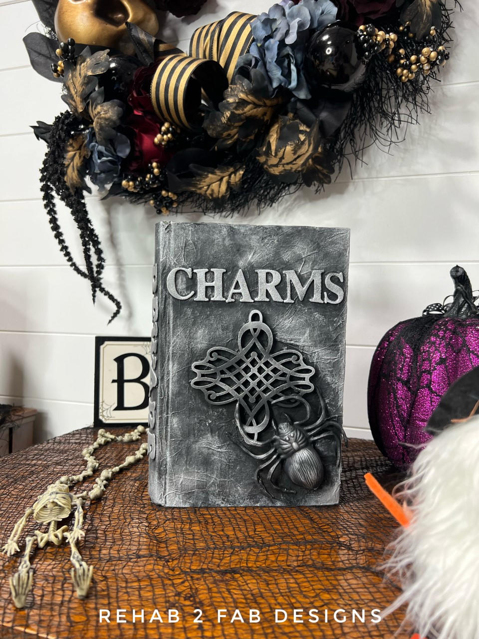 Dixie Belle Paint Midnight Sky Chalk Mineral Paint is the perfect paint for any DIY project! Black Chalk painted Halloween Charm Book décor. Staged with a skeleton, some purple pumpkins and a Halloween themed wreath.