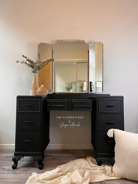 Dixie Belle Paint Midnight Sky Chalk Mineral Paint is the perfect paint for any DIY project! Black Chalk painted vanity desk. Staged with two wood vases and a plant inside.
