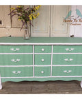 Dixie Belle Paint Mint Julep Chalk Mineral Paint is the perfect paint for any DIY project!
White chalk painted dresser with mint green chalk painted drawer fronts and top. Staged with a vase and yellow flowers.