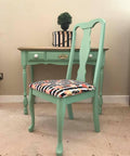 Dixie Belle Paint Mint Julep Chalk Mineral Paint is the perfect paint for any DIY project!
Mint Chalk Painted desk and chair with a  black and white strip patterned with pink and gold paint splatter fabric on top of chair. Staged with  a Black and white stripe box and plant on top.