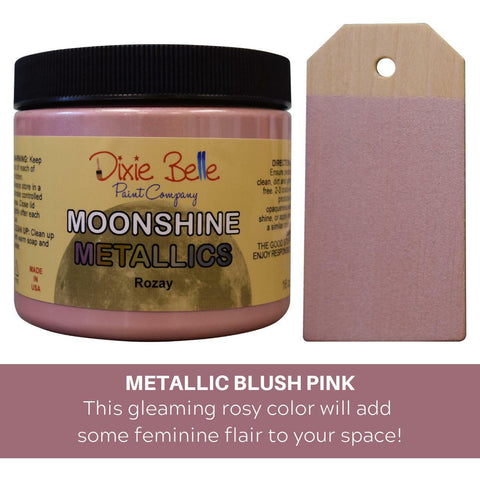 Rozay Moonshine metallic is the perfect paint to add shimmer and shine to your chalk painted furniture. Metallic blush pink, this gleaming rosy color will add some feminine flair to your space. 16 oz. Jar of Rozay Moonshine Metallic next to a sample on wood.