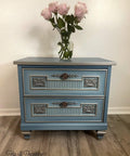 Moonshine metallic is the perfect paint to add shimmer and shine to your chalk painted furniture. Blue chalk painted end table with Grayish metallic chalk mineral paint accents. Staged with a glass vase and pink roses.