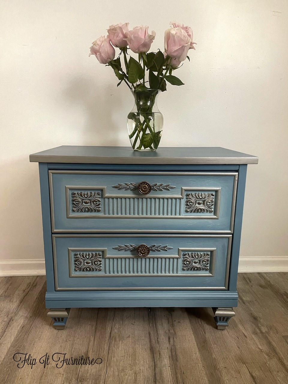 Moonshine metallic is the perfect paint to add shimmer and shine to your chalk painted furniture. Blue chalk painted end table with Grayish metallic chalk mineral paint accents. Staged with a glass vase and pink roses.