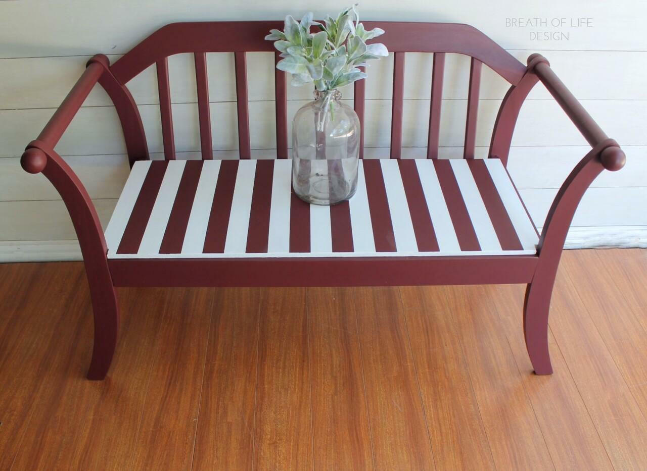 Dixie Belle Paint Muscadine Wine Chalk Mineral Paint is the perfect paint for any DIY project! Bench painted with dark red Chalk Mineral Paint with white stripes on the seat. Staged with glass vase and plants inside.
