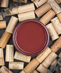 Dixie Belle Paint Muscadine Wine Chalk Mineral Paint is the perfect paint for any DIY project! Top view of deep red open paint can with wine corks around it.