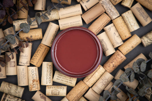 Dixie Belle Paint Muscadine Wine Chalk Mineral Paint is the perfect paint for any DIY project! Top view of deep red open paint can with wine corks around it.