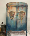 Dixie Belle Paint Patina Paint. Blue Chalk Painted armoire made to look rusty and distressed with Patina Paint.  Staged with a metal bucket with lotus pods and candle holders.