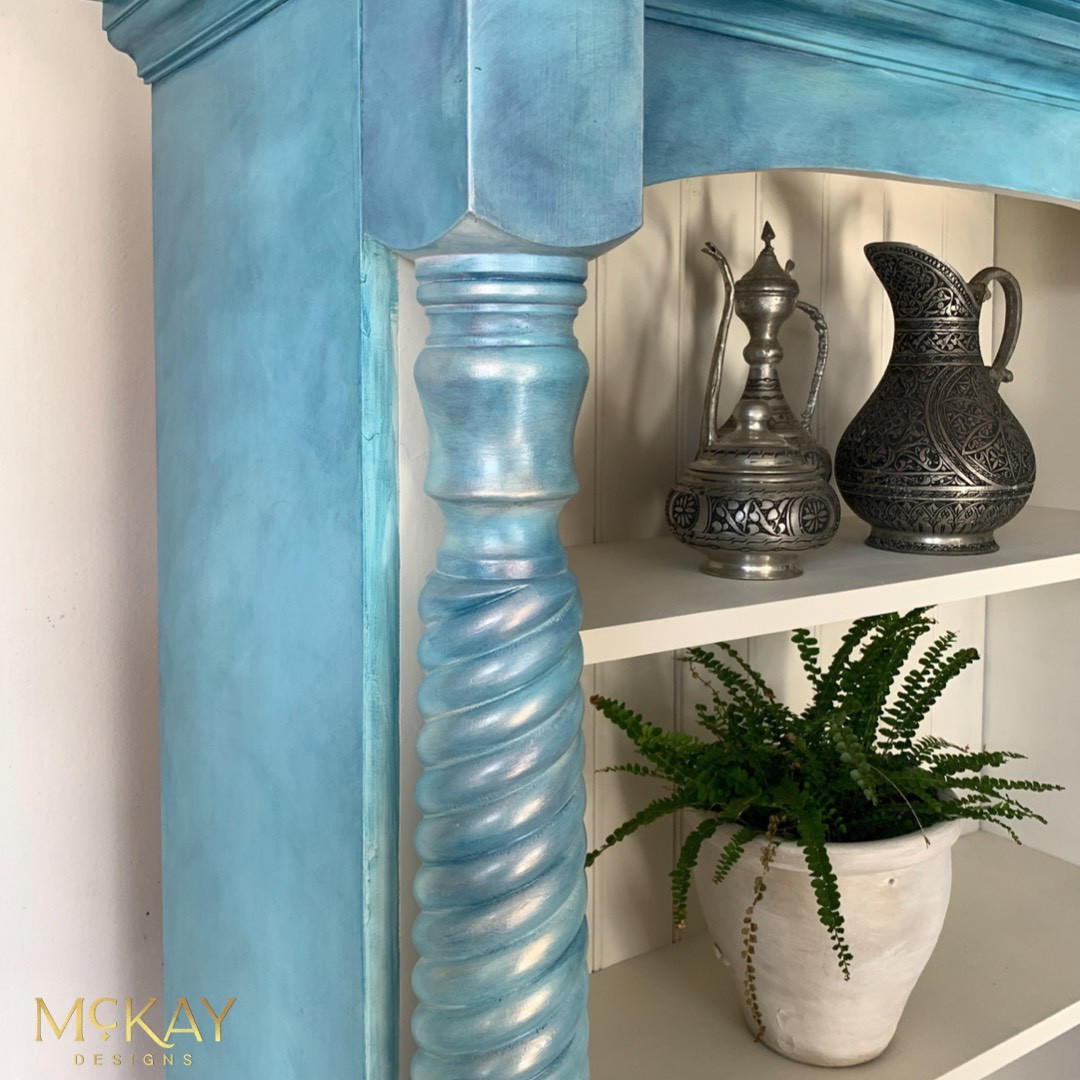 Dixie Belle Paint Pearlescent Glaze. Up-close of a Blue chalk painted piece of furniture with Pearlescent Glaze. Staged with a plant and some metal pitchers,