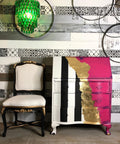 Dixie Belle Paint Peony Chalk Mineral Paint is the perfect paint for any DIY project! Secretary desk with one side painted black and white stripes and other side painted pink chalk paint with gold stripe down the middle. Staged next to a black and white chair with gold on it.