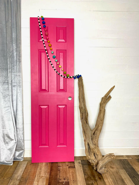 Dixie Belle Paint Peony Chalk Mineral Paint is the perfect paint for any DIY project! Pink chalk painted door staged next to wood and wood beads hanged on.