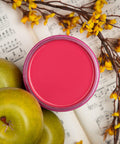 Dixie Belle Paint Peony Chalk Mineral Paint is the perfect paint for any DIY project! Top view of pink chalk paint can open staged next to apples, a plant and music sheets.