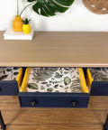 Dixie Belle Paint Pine Cone Chalk Mineral Paint is the perfect paint for any DIY project!  Chalk mineral painted desk with a light brown chalk paint on the top and dark blue for the body. With a tropical leaves print in the drawers. Staged with pineapples and plants.