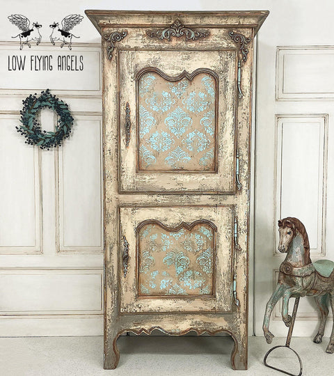 Dixie Belle Paint Pine Cone Chalk Mineral Paint is the perfect paint for any DIY project! Light brown Chalk mineral painted armoire distressed to make look chippie. Blue scroll style stencil painted on the front doors. Staged with a wreath and a vintage horse statue.
