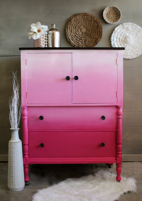 Dixie Belle Paint Pink Champagne Chalk Mineral Paint is the perfect paint for any DIY project! Pink Ombre chalk painted dresser goes from dark to light pink.  Staged with flowers and wicker baskets on the wall.
