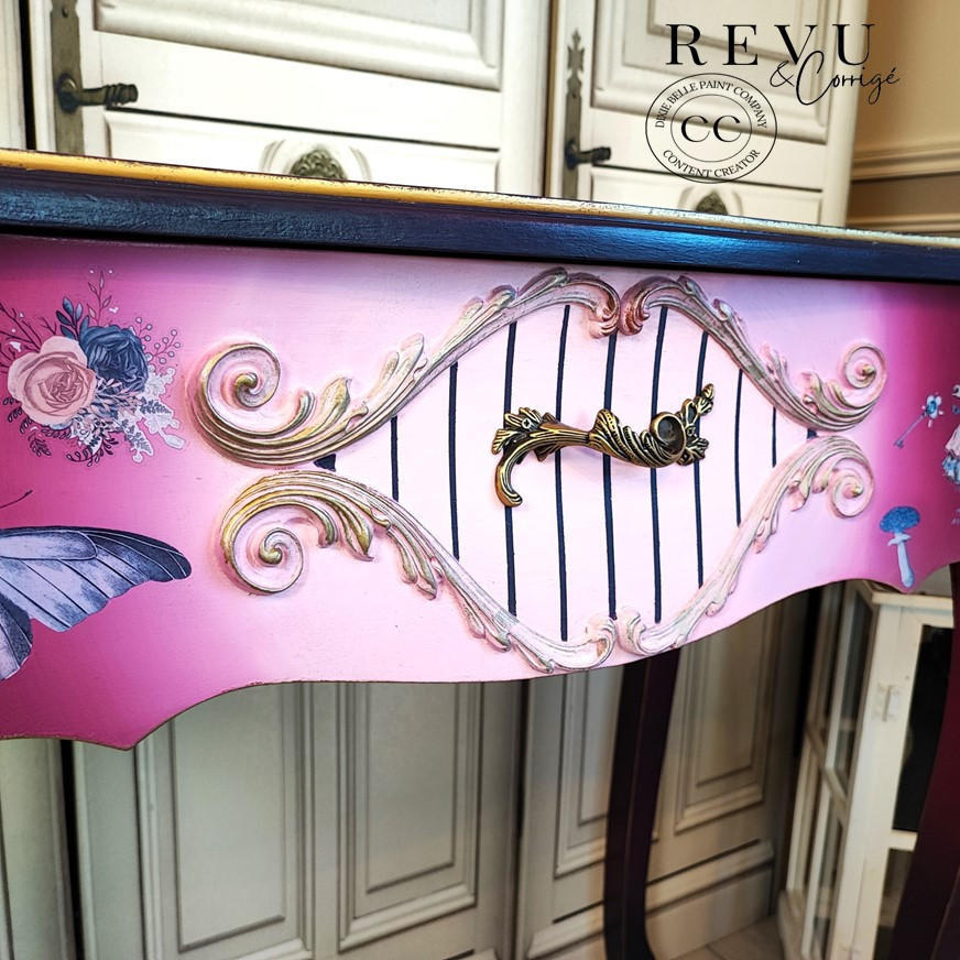 Dixie Belle Paint Plum Crazy Chalk Mineral Paint is the perfect paint for any DIY project! Up close of an end table painted in a maroon and pink chalk paint Ombre with black strips in the middle and gold on the trim with floral rub on transfers.