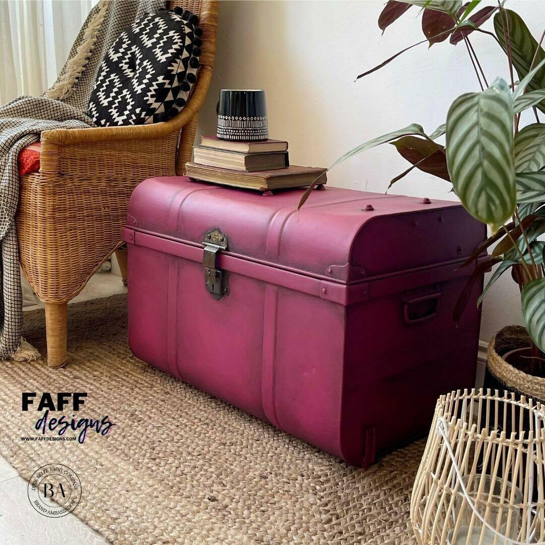 Dixie Belle Paint Plum Crazy Chalk Mineral Paint is the perfect paint for any DIY project! Maroon chalk painted trunk with bronze hard ware and black blended to give it an old look. Staged with book and a black flower pot.