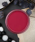 Dixie Belle Paint Plum Crazy Chalk Mineral Paint is the perfect paint for any DIY project! Open top view of a maroon chalk paint. Staged with black and white wood beads and black floral plants.