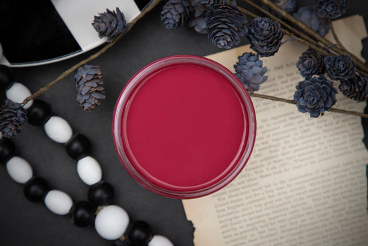 Dixie Belle Paint Plum Crazy Chalk Mineral Paint is the perfect paint for any DIY project! Open top view of a maroon chalk paint. Staged with black and white wood beads and black floral plants.