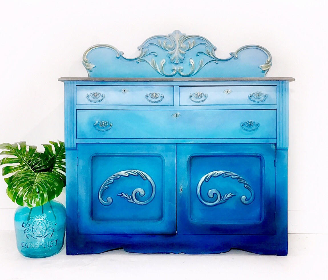 Dixie Belle Paint Pure Ocean Chalk Mineral Paint is the perfect paint for any DIY project! dark blue to light blue Ombre chalk painted cabinet with glass vase and a leaf.