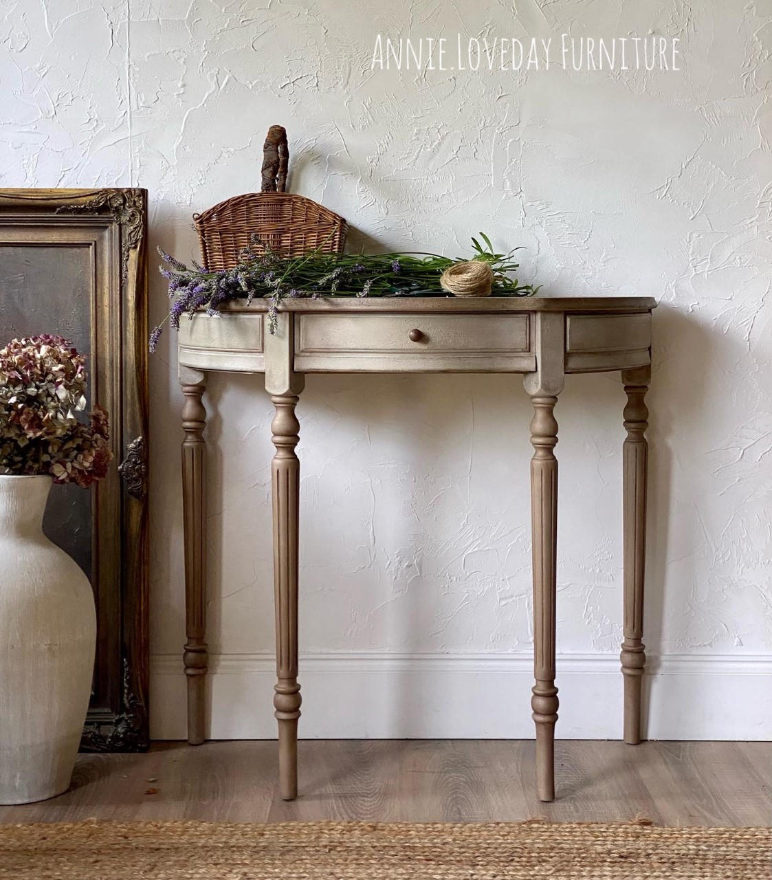 Dixie Belle Paint Putty Chalk Mineral Paint is the perfect paint for any DIY project! A half moon hallway table in a neutral tone paint with lavender staged on top with a big vase and picture frame to the left of the table.