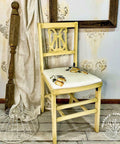 Dixie Belle Paint Rebel Yell-ow Chalk Mineral Paint is the perfect paint for any DIY project! A kitchen chair with this vintage yellow color all over the frame with a white seat. The white seat has a lemon transfer on top and it is staged with various household items.