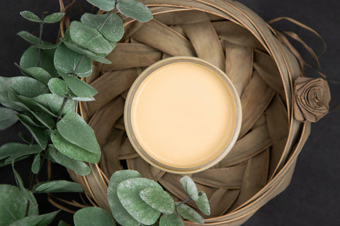 Dixie Belle Paint Rebel Yell-ow Chalk Mineral Paint is the perfect paint for any DIY project! A top shot of this vintage yellow opened jar of paint staged in a woven basket with greenery surrounding.