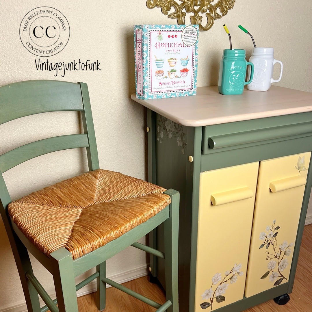 Dixie Belle Paint Rebel Yell-ow Chalk Mineral Paint is the perfect paint for any DIY project! A vintage rolling coffee cart painted in green and the door on the front are painted in this vintage yellow color with a transfer on the front and sides. To the left is a chair painted in the same green and the seat portion is wicker. The top is staged with an old cooking book and two painted mason jar mugs with a straw in each.
