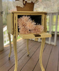 Dixie Belle Paint Rebel Yell-ow Chalk Mineral Paint is the perfect paint for any DIY project! This folding end table on wheels is sporting this vintage yellow throughout with a bit of distressing along the trim. This side table is staged on a porch and has the back open up into one opening with flowers and a basket on top of the end table.