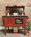 Dixie Belle Paint Rustic Red Chalk Mineral Paint is the perfect paint for any DIY project! A farmhouse bakery table featuring the rustic red and has a cupboard on the bottom. The bakery table is staged with various kitchen decor.
