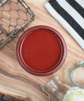 Dixie Belle Paint Rustic Red Chalk Mineral Paint is the perfect paint for any DIY project! A staged image of an open paint jar featuring the rustic red shade.