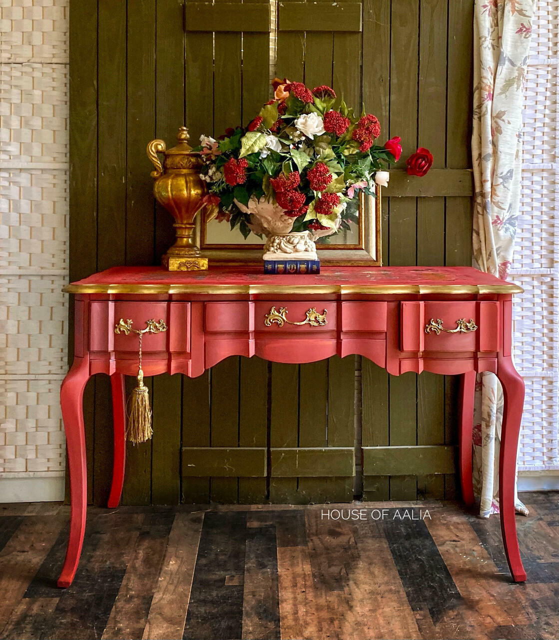 Dixie Belle Paint Rustic Red Chalk Mineral Paint is the perfect paint for any DIY project! A vintage table featuring the rustic red and the sides and hardware are accentuated with gold. This table has a gloss sheen and is staged with flowers and books on top.