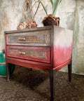 Dixie Belle Paint Rustic Red Chalk Mineral Paint is the perfect paint for any DIY project! A single bedside table that has the rustic red starting at the base of the table and is blended into white at the top. This bedside table has a rustic feel and is staged with various household decor items.