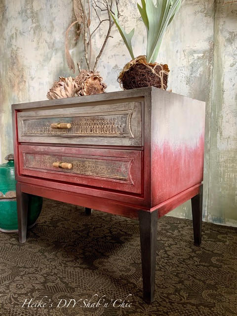 Dixie Belle Paint Rustic Red Chalk Mineral Paint is the perfect paint for any DIY project! A single bedside table that has the rustic red starting at the base of the table and is blended into white at the top. This bedside table has a rustic feel and is staged with various household decor items.