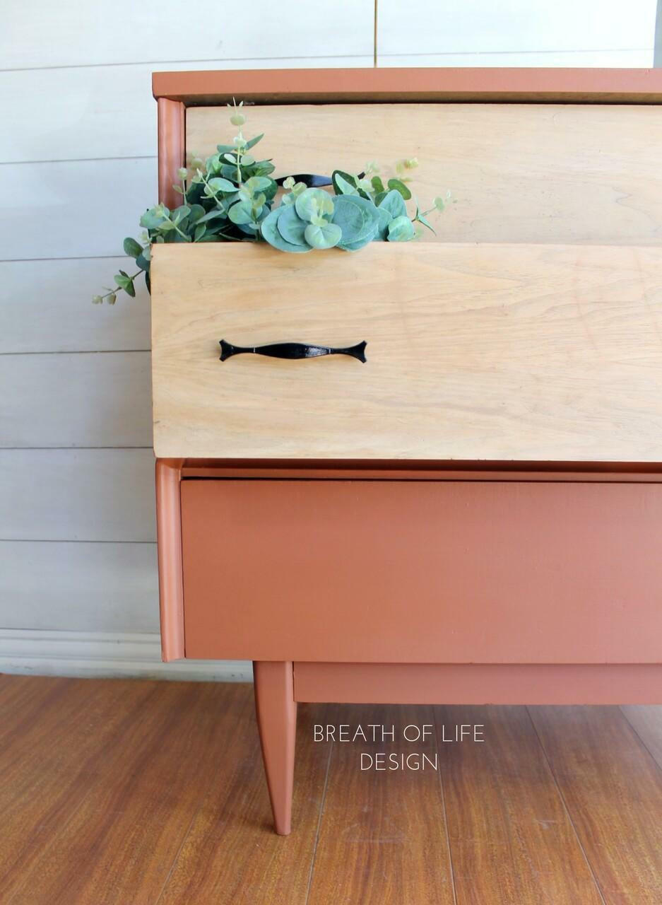 Dixie Belle Paint Rusty Nail Chalk Mineral Paint is the perfect paint for any DIY project! A closeup image of the MCM dresser showing the bottom of the dresser painted in rusty nail and the drawers natural wood.