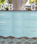 Dixie Belle Paint Sea Glass Chalk Mineral Paint is the perfect paint for any DIY project! A dresser painted in sea glass with silver hardware and is staged outside.