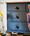 Dixie Belle Paint Sea Spray creates a chippy, textured & weathered look when mixed with your favorite Dixie Belle color. A black dresser with a hand-painted lady on the front with a blended cloud of blue. These colors on this dresser is accompanied by sea spray to give it texture.