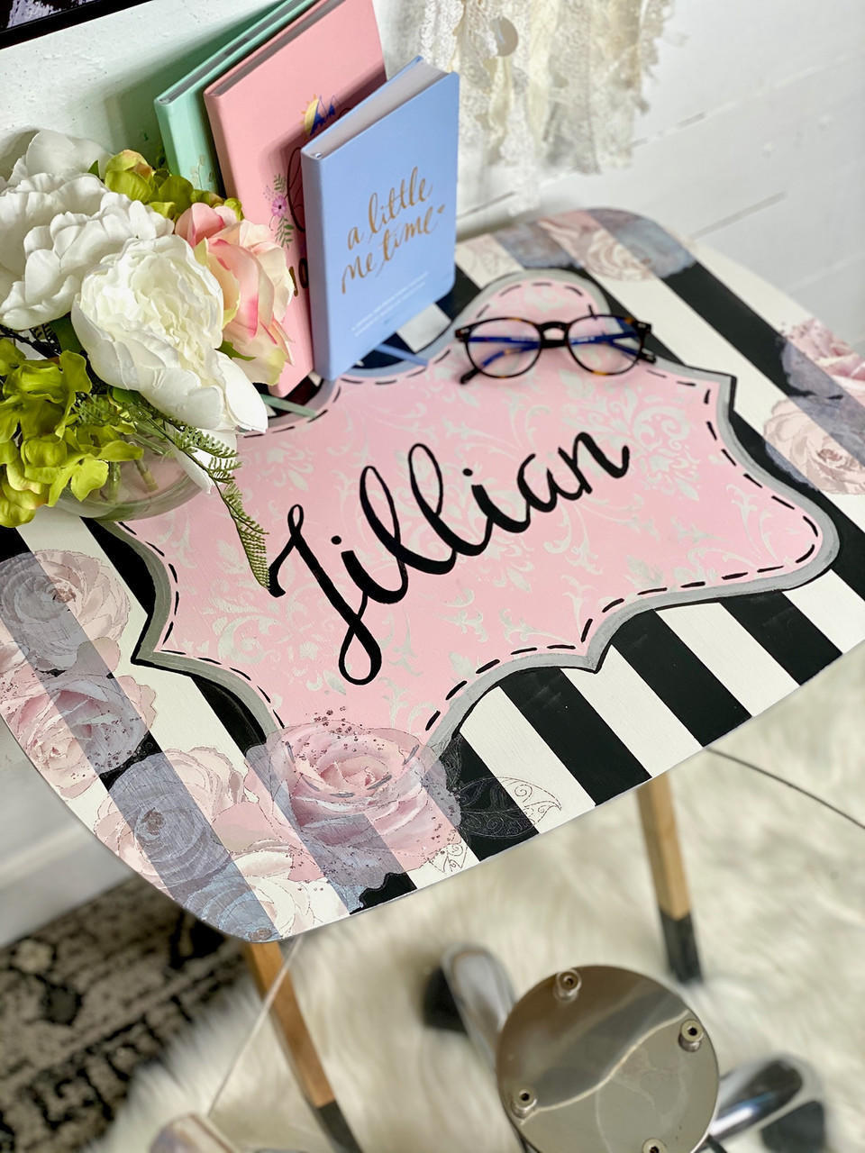 Dixie Belle Paint Soft Pink Chalk Mineral Paint is the perfect paint for any DIY project! A reading table that is painted in soft pink chalk mineral paint as a base color and thick black stripes on the top. There is a handwritten name "Jillian" on the top in black and the table is staged with reading glasses and various books.