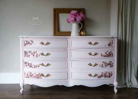 Dixie Belle Paint Soft Pink Chalk Mineral Paint is the perfect paint for any DIY project! A vintage dresser painted in soft pink chalk mineral paint and is accompanied by a cherry blossom transfer on each side of all 8 drawers.