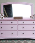 Dixie Belle Paint Soft Pink Chalk Mineral Paint is the perfect paint for any DIY project! A dresser with a mirror on top that is painted in soft pink chalk mineral paint and staged with home decor items.