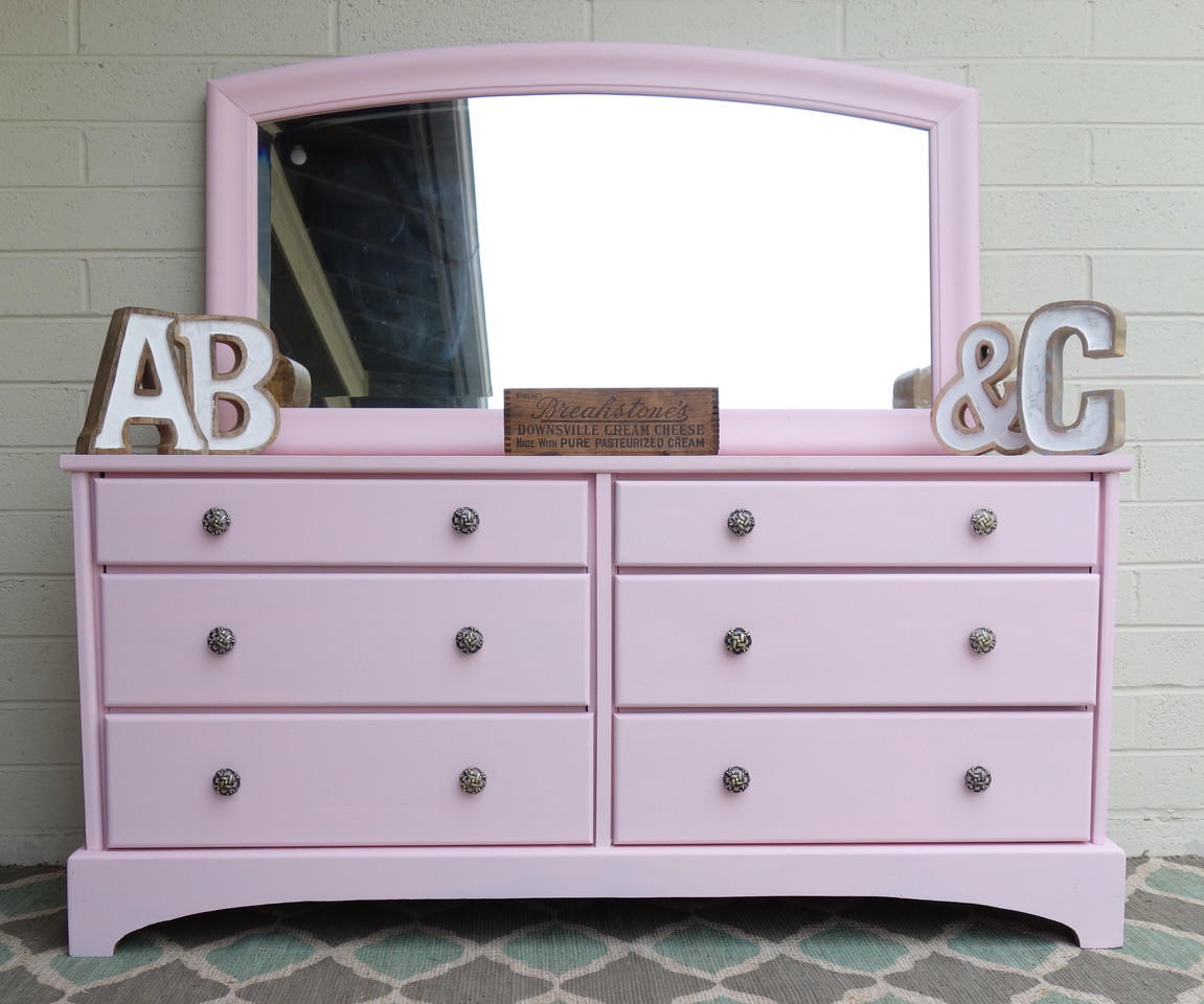 Dixie Belle Paint Soft Pink Chalk Mineral Paint is the perfect paint for any DIY project! A dresser with a mirror on top that is painted in soft pink chalk mineral paint and staged with home decor items.