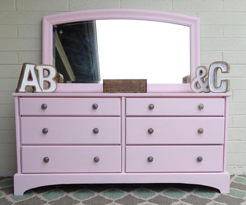 Dixie Belle Paint Soft Pink Chalk Mineral Paint is the perfect paint for any DIY project! A dresser with a mirror on top that is painted in soft pink chalk mineral paint and staged with home decor items.