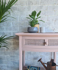 Dixie Belle Paint Soft Pink Chalk Mineral Paint is the perfect paint for any DIY project! A simple side table painted in soft pink chalk mineral paint and has a rattan type of design on the front single drawer.