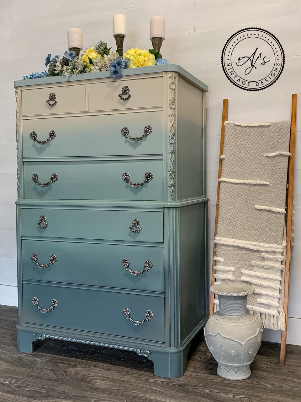 Dixie Belle Paint Stormy Seas Chalk Mineral Paint is the perfect paint for any DIY project!
Tall dresser Painted tan ombre to Stormy Seas with silver hardware. Staged with blue,yellow,white flowers along the top of dresser and three bronze candle holders in the back.