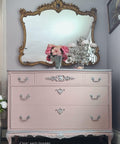 Dixie Belle Paint Tea Rose Chalk Mineral Paint is the perfect paint for any DIY project!
Beautiful elegant dresser given a makeover by painting it in Tea Rose Chalk Mineral Paint and using silver hardware with silver accent all around edge of the dresser. Staged with chandelier looking piece with flowers around and a clear glass vase.