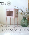 Dixie Belle Paint Tea Rose Chalk Mineral Paint is the perfect paint for any DIY project!
Bedside table painted in Tea Rose Chalk Mineral Paint  with the Magnolia Garden  Transfer on the side panels. Staged on a boho light tan rug and a large green round glass flower vase.