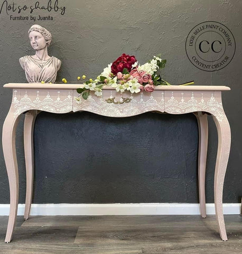 Dixie Belle Paint Tea Rose Chalk Mineral Paint is the perfect paint for any DIY project!
Entrance table painted in Tea Rose Chalk Mineral Paint with Lotus Bloom - Stencil along the front drawer. Staged with flowers and torso statue of a women on top of piece.