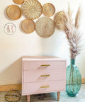 Dixie Belle Paint Tea Rose Chalk Mineral Paint is the perfect paint for any DIY project!
Bedside table painted in Tea Rose Chalk Mineral Paint with gold hardware. Staged with 6 woven circles pieces hanging on the wall above.