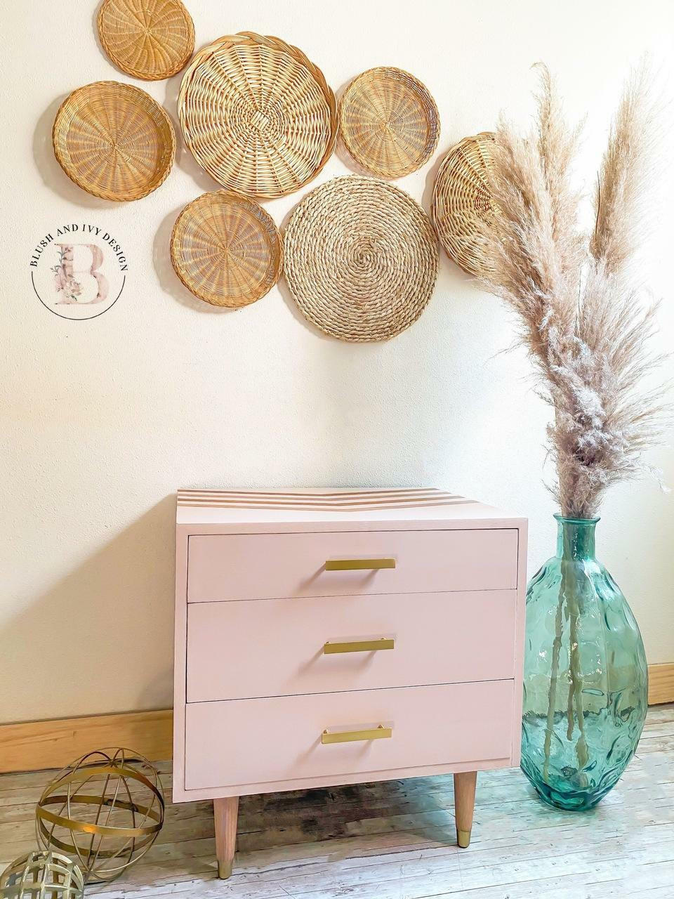 Dixie Belle Paint Tea Rose Chalk Mineral Paint is the perfect paint for any DIY project!
Bedside table painted in Tea Rose Chalk Mineral Paint with gold hardware. Staged with 6 woven circles pieces hanging on the wall above.