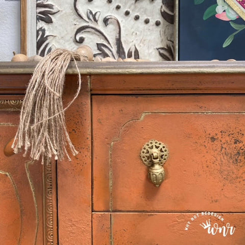 Dixie Belle Paint Terracotta Chalk Mineral Paint is the perfect paint for any DIY project!  A closeup picture of the front of a brown chalk painted dresser with a gold pull knob and a tassel hanging off of it.